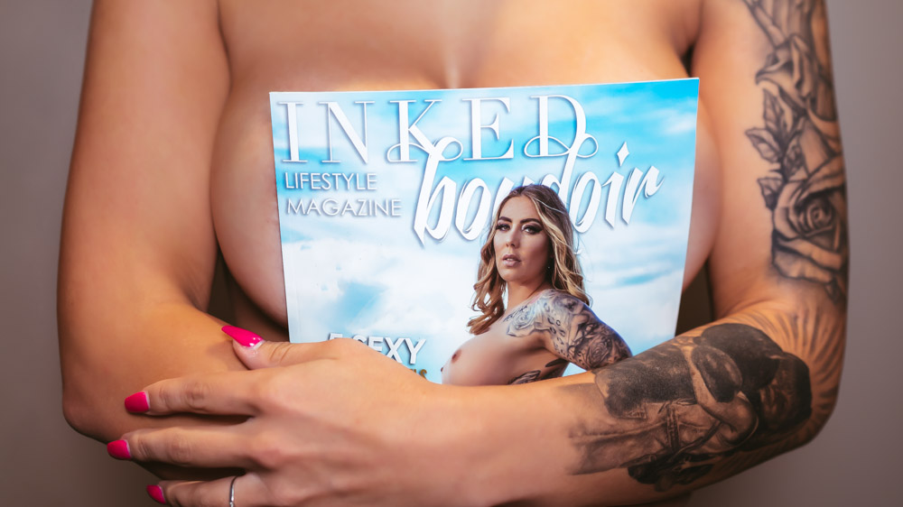 INKED boudoir model Tattooed Dark Heart magazine in front of breast